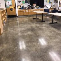 Grind and Shine 3 (1) The image shows an indoor setting with polished concrete floors, office furniture including tables and desks, and informative boards on the walls.